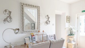 Une pièce comprenant une table en bois, une chaise, un miroir, une bibliothèque et une porte avec un panneau indiquant la sortie de secours.