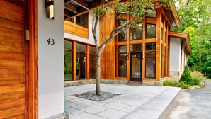 A modern building with a large wooden door, numbered 43, and a tree in front. - Luxurious Modern Home Steps to Gondola & Village (Stratton)
