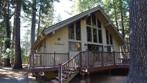 A cabin with a wooden deck and stairs leading to a porch. - Evergreen Dorrington • Both Cabins • Game Room • Hot Tub • Pool Access (Dorrington)