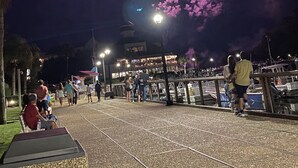 Une scène nocturne avec une grande structure circulaire illuminée dans le ciel, qui pourrait être un feu d’artifice.