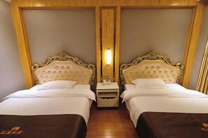 Habitación de hotel con dos camas, cada una con cabecera acolchada y ropa de cama blanca.
