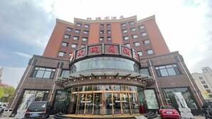 A hotel with a curved entrance, multiple floors, and a clear sky. - Rose Garden Hotel (Dalian)
