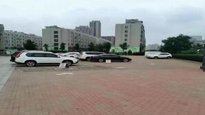 A parking lot with several cars and buildings in the background. - Rose Garden Hotel (Dalian)