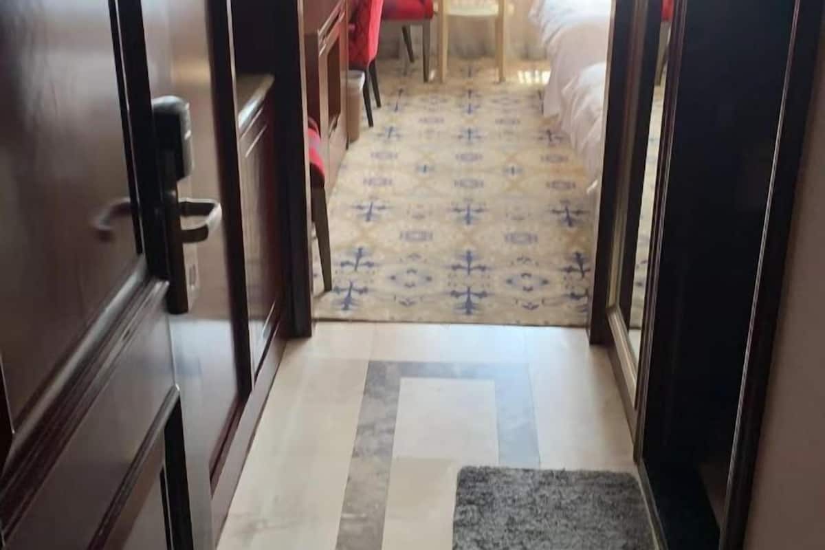 A hotel hallway with a patterned carpet, a small rug, and wooden furniture.