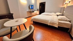 Una habitación de hotel con dos camas, una mesita y un televisor.