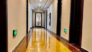 Un pasillo largo y pulido, con piso brillante, que conduce a una puerta al final.