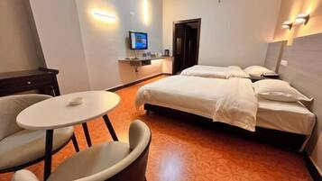 A hotel room with two beds, a small table, and a TV.