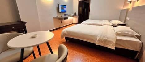 Habitación de hotel con dos camas, una mesita y un televisor.