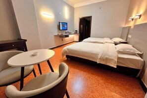 Habitación de hotel con dos camas, una mesita y un televisor.