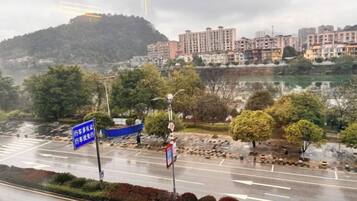 Una carretera con un cartel azul, árboles y edificios al fondo.