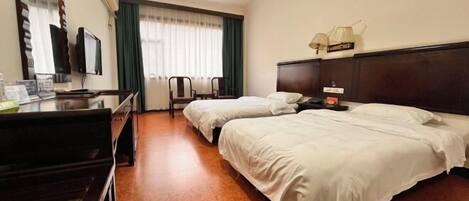 A hotel room with two beds, a desk with a television, a mirror, and a window with curtains.