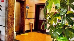 Un vestíbulo de hotel con suelo de mármol, un mostrador de recepción y una gran planta en maceta.