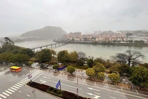 Un río con un puente, edificios y una calle con un autobús.