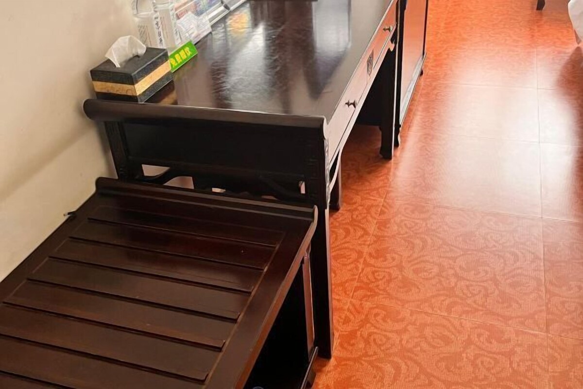 Un banco de madera y una mesa con una caja de pañuelos y un objeto verde encima.
