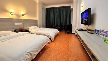A hotel room with two beds, a TV, a desk, and a large window with curtains.