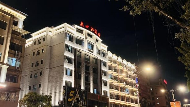Un hotel de varios pisos con un llamativo letrero '5X', que indica una calificación de 5 estrellas.