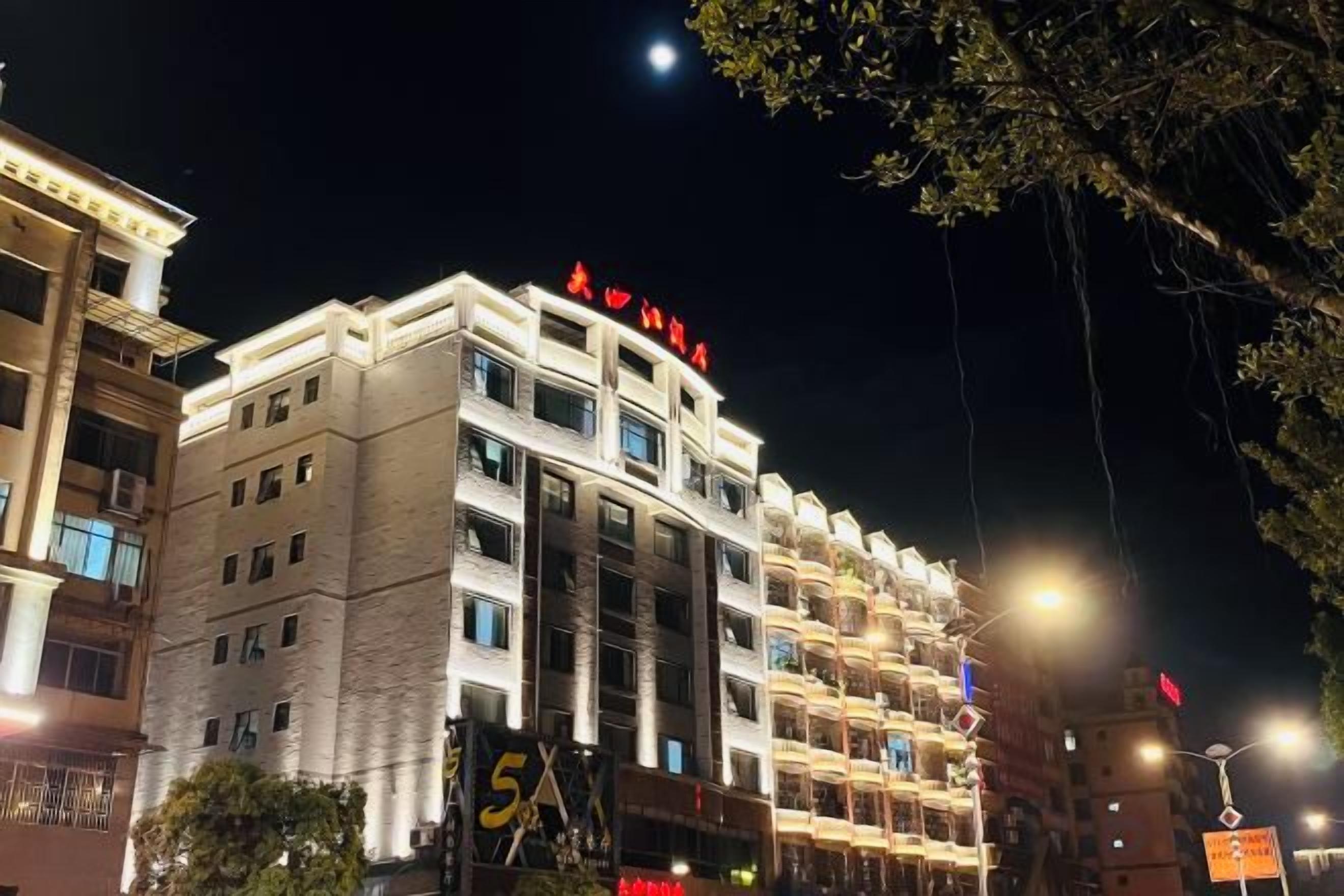 A multi-story hotel with balconies, illuminated signage, and a clear night sky.