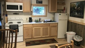Una cocina con armarios de madera, estufa, microondas, fregadero y refrigerador.