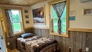 Un dormitorio acogedor con cama, una mesita con un libro y una ventana con cortinas.