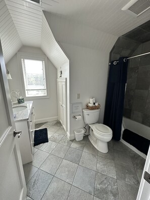 Een bad/douchecombinatie, een haardroger, handdoeken, toiletpapier