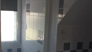 Uma casa de banho com chuveiro, sanita e lavatório.