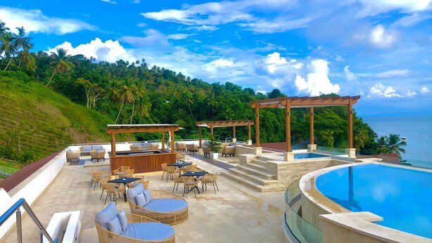 A poolside area with outdoor seating, a pergola, and a view of the ocean. - Beautiful 2 bedroom 3 bed  condominium with big balcony  (Samaná Province)