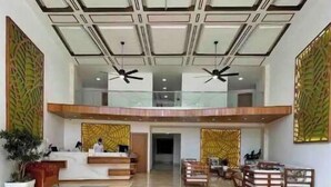 A spacious lobby with a high ceiling, two reception desks, seating area, and decorative wall panels. - Beautiful 2 bedroom 3 bed  condominium with big balcony  (Samaná Province)