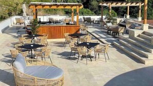An outdoor patio area with wicker furniture, a bar, and a view of a hillside with palm trees. - Beautiful 2 bedroom 3 bed  condominium with big balcony  (Samaná Province)