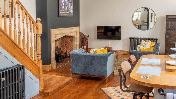 Uma sala de estar moderna com lareira, área de jantar e escada.
