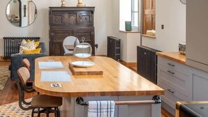 Uma cozinha moderna com ilha central, piso de madeira e vista para a sala de estar.