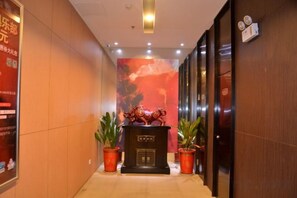 A hotel reception area with a reception desk, potted plants, and a large wall mural. - Jinjiang Inn (Suqian Development Area Xihu Road) (Suqian)