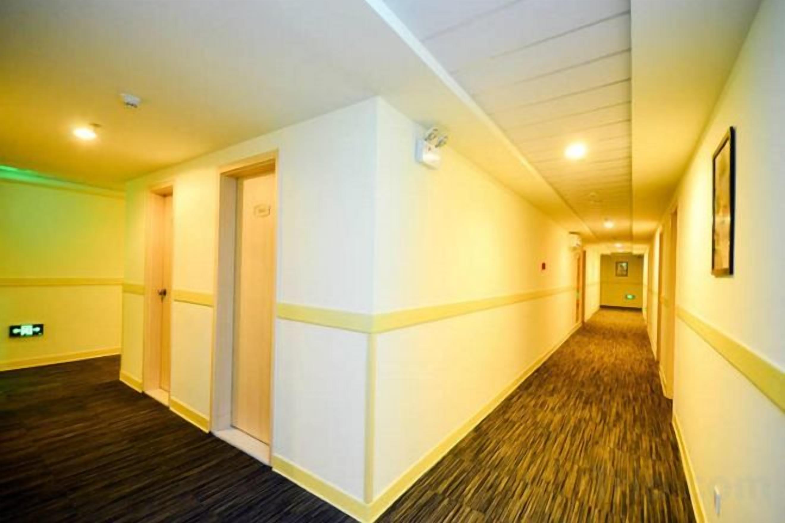 Un couloir d'hôtel avec des revêtements de sol en moquette, des portes et un tableau encadré accroché au mur.