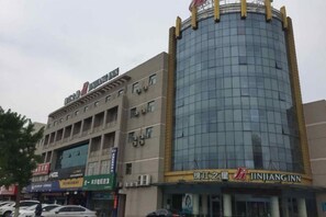 A multi-story building with a glass facade, signage for a restaurant, and a visible entrance. - Jinjiang Inn (Suqian Development Area Xihu Road) (Suqian)