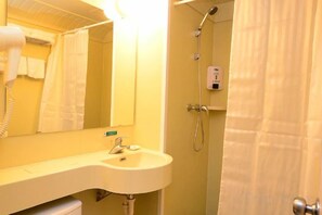 Un baño con lavamanos, espejo y ducha.