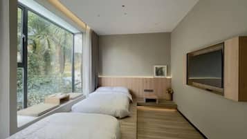 A modern hotel room with two beds, a large window, a wooden floor, and a mounted TV.