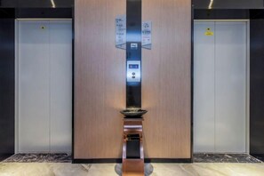 An elevator with a control panel and a digital display, flanked by two closed elevator doors. - Borrman Hotel (Chongqing Ronghui Peninsula) (Chongqing)