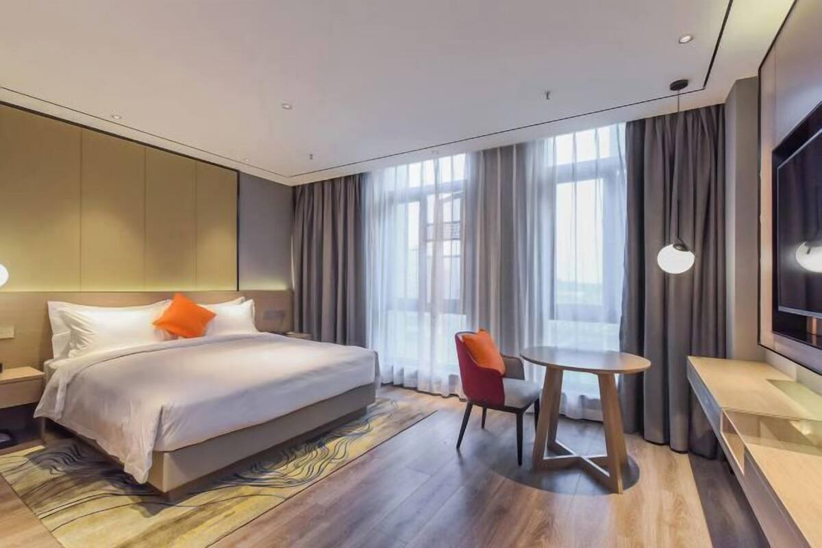 Ein modernes Hotelzimmer mit einem großen Bett, einem kleinen runden Tisch und einem Fernseher.