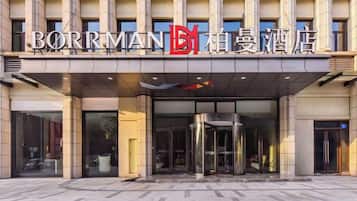 A hotel entrance with a modern design, featuring a glass facade and a revolving door.