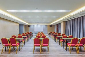 A conference room with rows of tables and chairs, a projector screen, and curtains on the walls. - Borrman Hotel (Chongqing Ronghui Peninsula) (Chongqing)