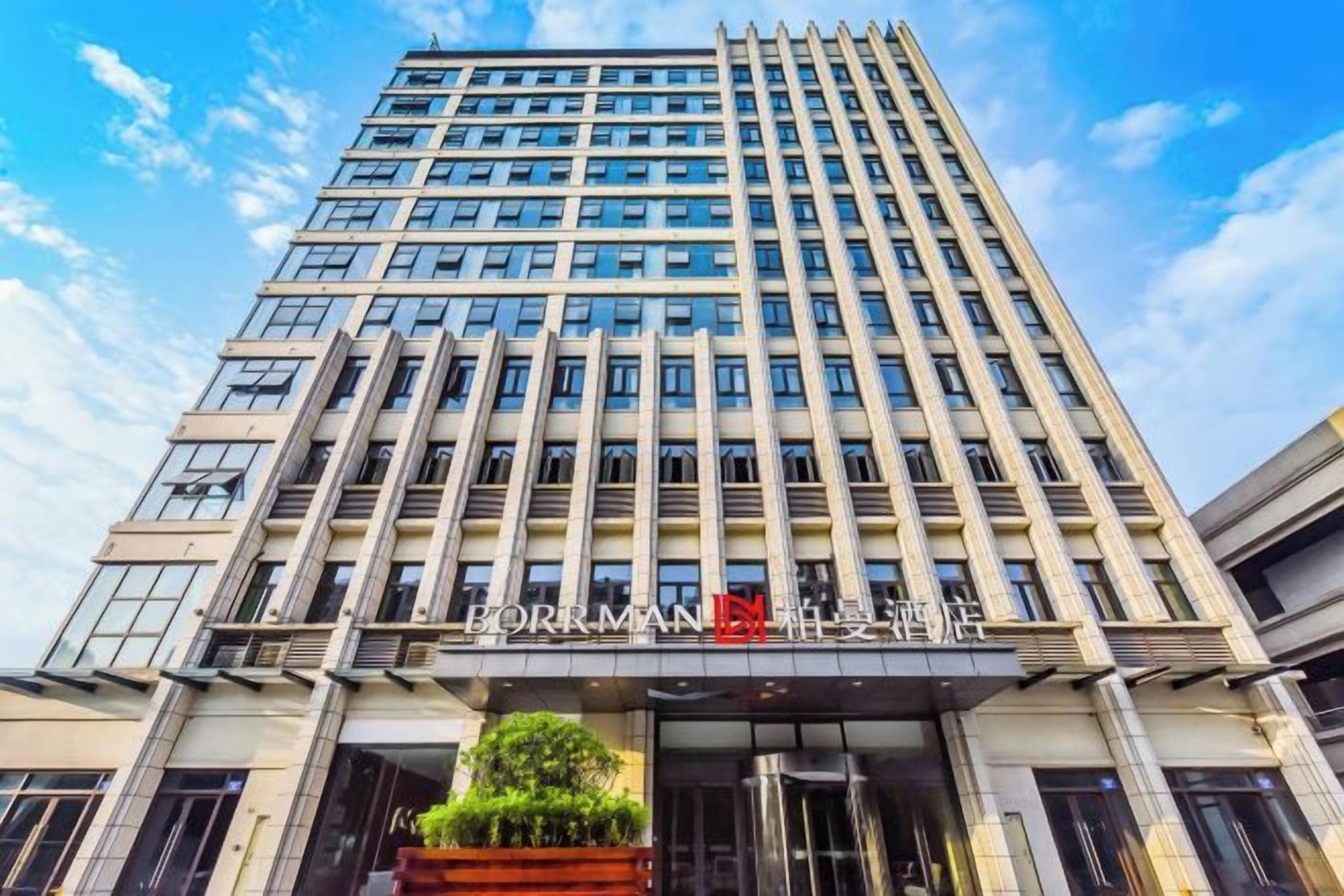 Un edificio alto de diseño moderno, con una entrada destacada de fachada de vidrio y un cartel sobre las puertas.