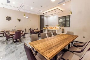 A conference room with a long wooden table, multiple chairs, and a kitchen area. - Borrman Hotel (Chongqing Ronghui Peninsula) (Chongqing)