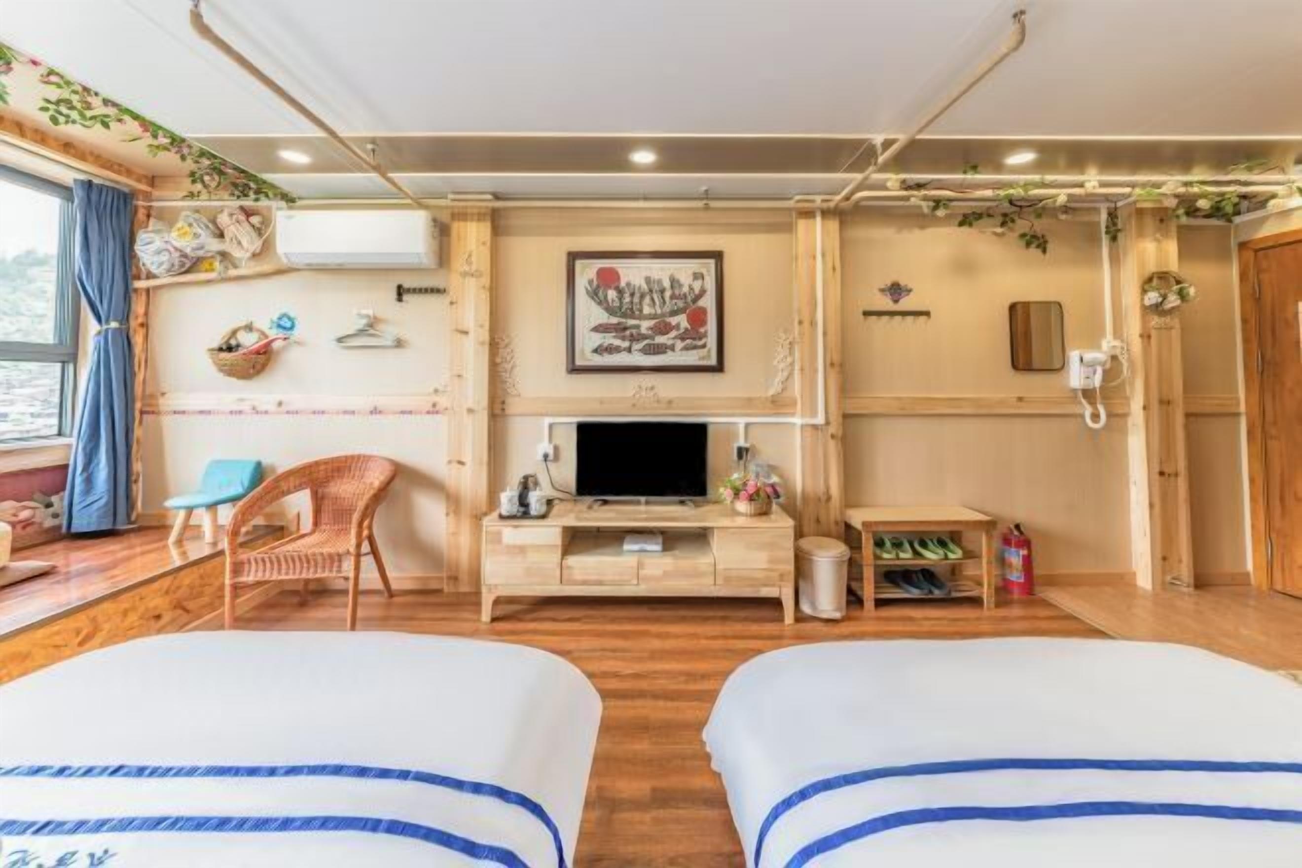 Quarto com duas camas, televisão, armário de madeira, cadeira e janela com cortinas.