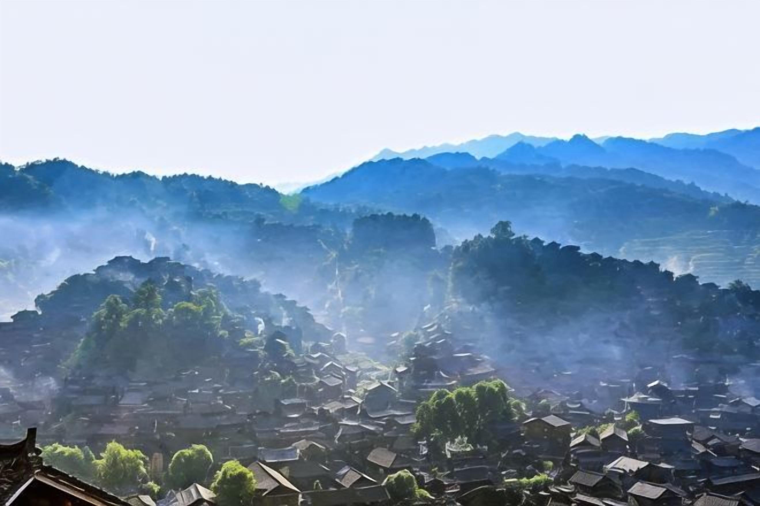 A village with traditional architecture, terraced fields, and a mountainous backdrop.