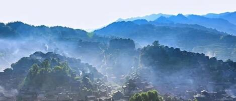 A village with traditional architecture, terraced fields, and a mountainous backdrop.
