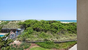 Vue d’une plage avec une terrasse en bois et un espace piscine.