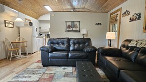Un salon avec un canapé en cuir noir, un pouf assorti et un tapis à motifs.