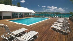 Zona de piscina con sillones de descanso y vista al mar.