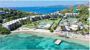Un resort con varias edificaciones, una playa y aguas azules cristalinas.