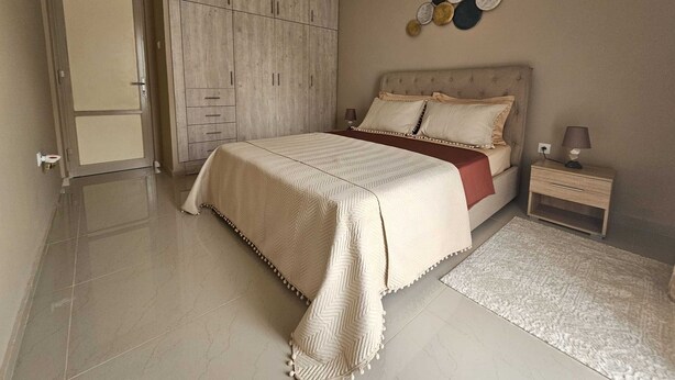 Een slaapkamer met een bed, nachtkastje en kledingkast.