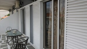 Een balkon met een glazen deur, een tafel met stoelen en een potplant.
